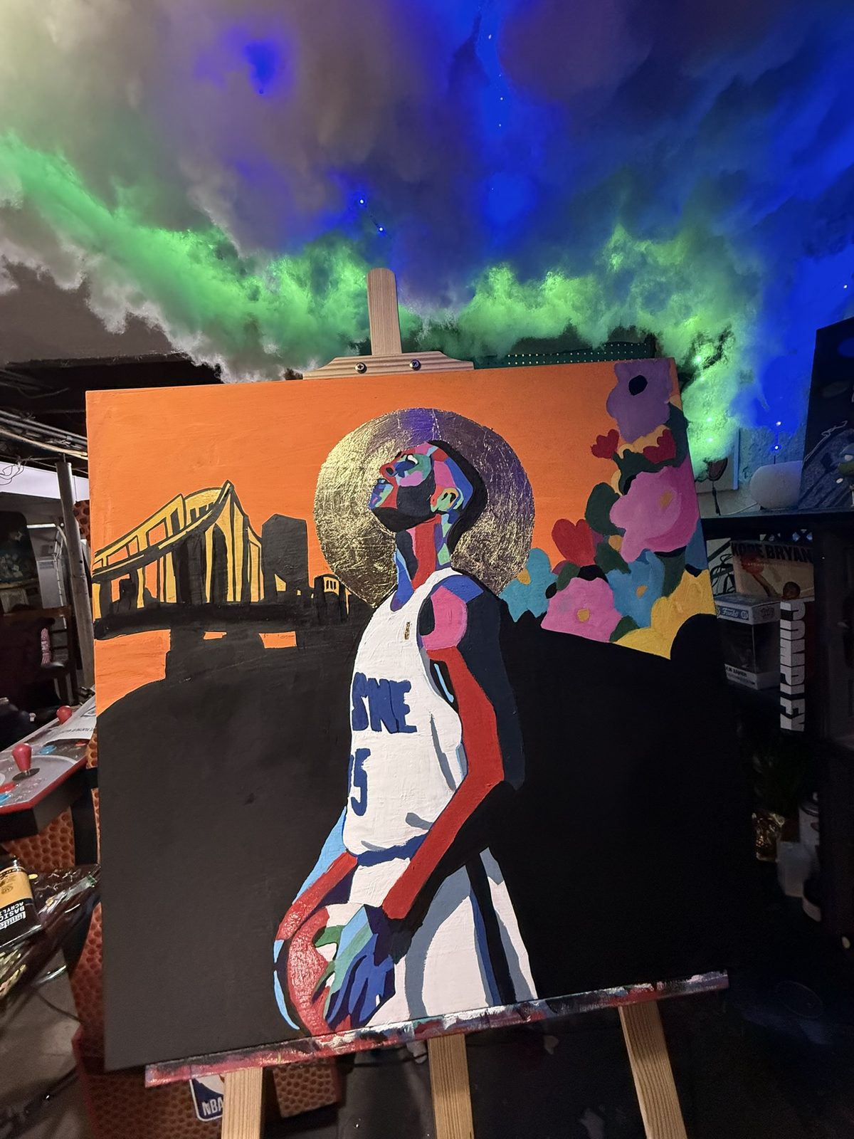 Painting of a figure in a Duquesne jersey with a gold leaf halo against the Pittsburgh skyline, with flowers blooming beside them.